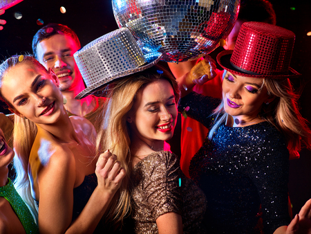 Dance party with group people dancing . Women and men have fun in night club. Happy girl on foreground and disco ball on background.の写真素材