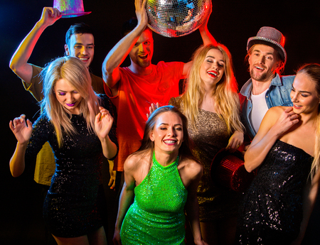 Dance party with group people dancing . Women and men have fun in night club. Happy girl in green...