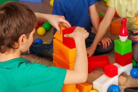 Children building blocks in kindergarten. Group kids playing toy on floor. Top view of interior preschool. Building tower of cubes. Independent childrens creativityの写真素材