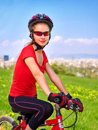 Escape urban. Bicycle girl has rest from city bustle. Woman wearing sport helmet rides returns into urbanization. Respect for environment. Factory pipes in background. Teenager in a summer camp.の写真素材