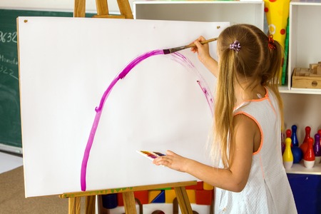 Children painting finger on easel. Group of kids girl and boy with teacher learn paint in class school. Child picture on background. Students draw a rainbow. Good psychological state of child.の写真素材