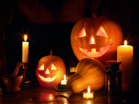 Halloween Jack O Lantern pumpkin head stacked at Halloween night with burning candles on black background.の写真素材