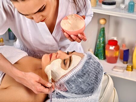 Collagen face mask. Facial skin treatment. Face of elderly elderly woman 50-60 years old receiving cosmetic procedure in beauty salon close up. Healing clay for the face.の写真素材