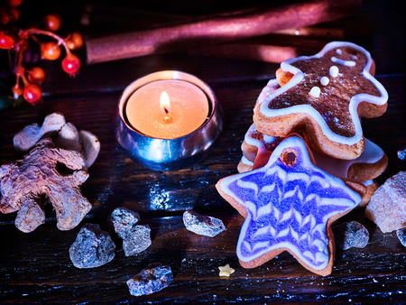 Candle light table with Christmas gingerbread cookies and cinnamon stick and star sweets are on wooden table and burning candles. Xmas still life object. Cookie is slide.の写真素材