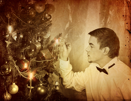 Man alone put up Christmas tree. Expectation of holiday on eve of Xmas party at home alone. Black and white Xmas vintage image.の写真素材