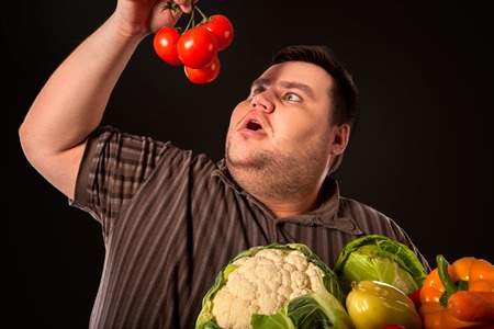 Diet fat man eating healthy food. Stop obesity concept. Male trying to lose weight and rejoices in healthy eating.の写真素材
