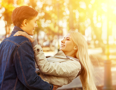 Spring couple walking park and kissing. Summer friends walk outdoor. First date and kiss of two young people in good weather day. Sunlight in sunset or sunrise. Beginning of first love.の写真素材