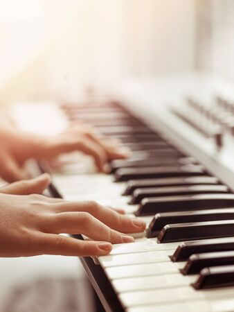 Midi keyboard or electronic piano and playing child hands. Musical education for kid in music school. Private lessons of music with a teacher for school-age children.の写真素材