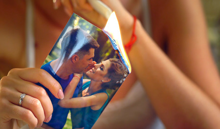 Wedding bride hands sitting night table. Couple quarrel during honeymoon. Boyfriend left girlfriend. Close up leaved hand woman burns photos of ex-boyfriend.の写真素材