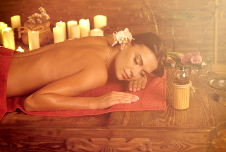 Massage Filipino of woman in spa salon. Girl candles in massage spa salon. Sun flare luxary interior in oriental therapy. Dry flowers in clay vases. Color tone on shiny sunlight background.の写真素材