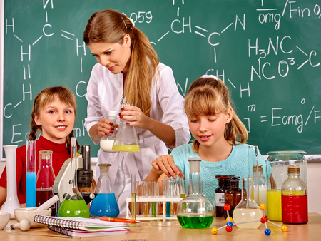 Teacher with children holding flask in chemistry class. Studies of chemistry.の写真素材