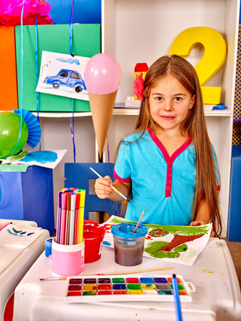 Portrait of little girl with brush painting on table in  kindergarten .の写真素材