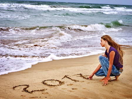 Summer girl sea.  Girl is writting in sand  2017 near ocean with waves. Sea concept.