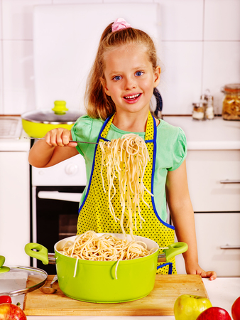 Children  eating spaghetti from pan at kitchen.の写真素材