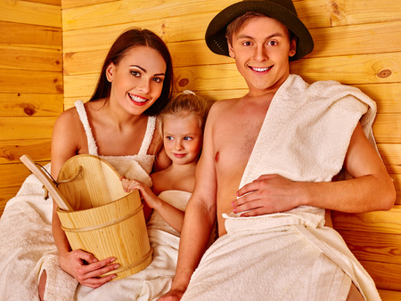 Happy family with one kid girl in hat  relaxing at saunaの写真素材