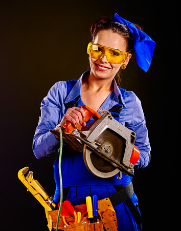 Happy woman builder in mask with circular saw on black background.の写真素材