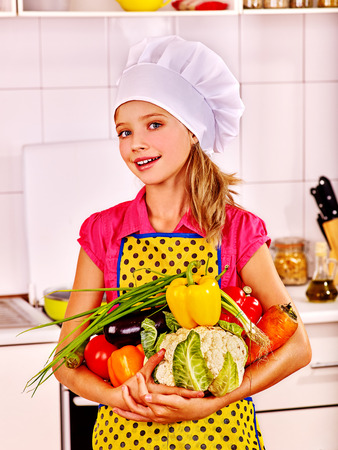 Teenager girl holding vegetable at kitchen.の写真素材