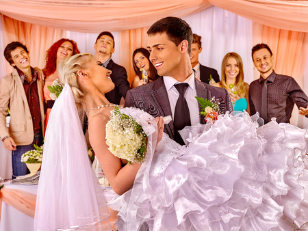Groom  carries bride on his hands  at wedding.の写真素材