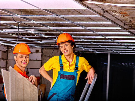 Men in builder uniform installing suspended ceilingの写真素材