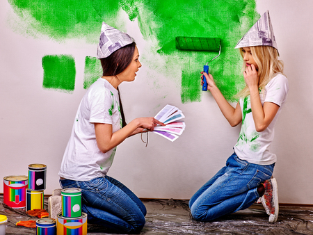 Happy woman in homamade newspaper hat paint wall at home.の写真素材