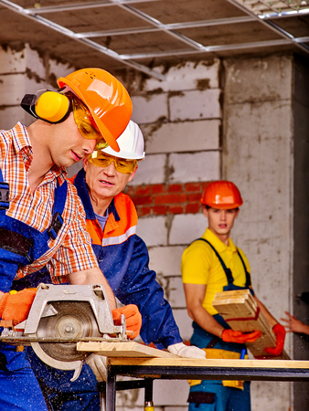 Happy group people  builder with circular saw working indoor.の写真素材
