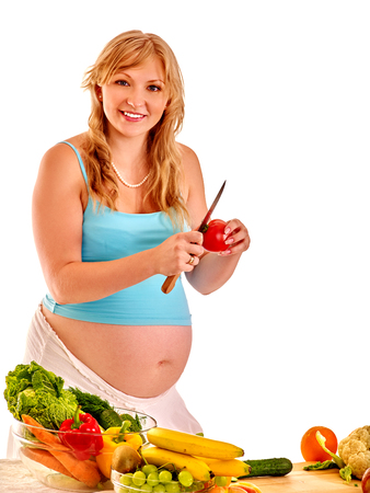 Pregnant woman preparing vegetable food in the kitchen Isolated.の写真素材