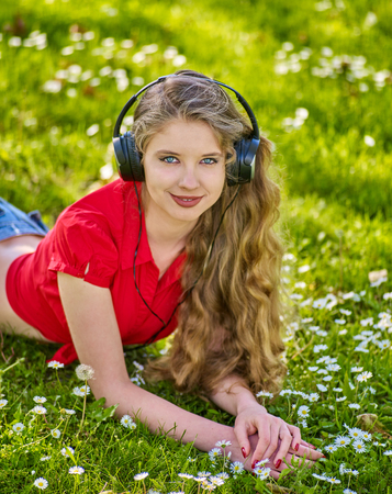 Girl in headphones catch rhythm music on green grass with chamomile flowers summer outdoor.の写真素材