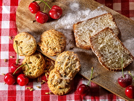 Oatmeal cookies and cherry on kitchen cutting board gingham checkered cotton fabric on table in village style for picnic. New dishes in expensive cafe. Culinary still life at exhibition.の写真素材