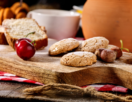Oatmeal cookies and cherry on kitchen cutting board gingham checkered cotton fabric on table in village style for picnic. Milk jug in background. Beautiful, expensive, culinary masterpieces.の写真素材