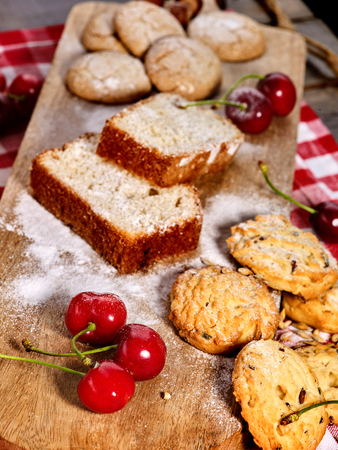 Oatmeal cookies and cherry on kitchen cutting board gingham checkered cotton fabric on table in village style for picnic. New dishes in expensive cafe. Festive table decoration.の写真素材