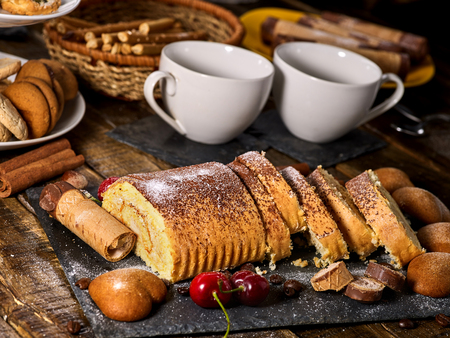 Cookies heart shape, sand rolled biscuit and cinnamon stick on wood table served dessert spoon at kitchen in rustic style. Morning sun flare. Breakfast for loved one.の写真素材