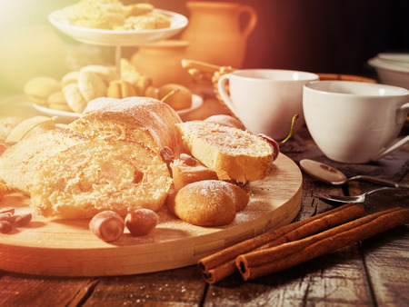 Sand nut chocolate cookies and rolled biscuit on board and cinnamon stick . Straw pastry with cup of coffee with dessert spoonon on wood kitchen table in rustic style .の写真素材