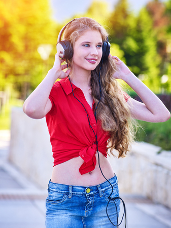 Girl in headphones and denim listens to music with closed eyes and sidewalk walking in city alone. Student life is period of opportunity to express yourself and your abilities.の写真素材