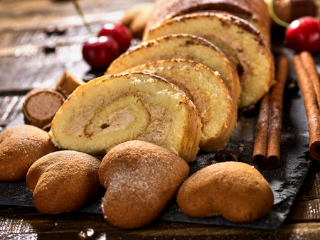 Cookies heart shape, sand rolled biscuit and cinnamon stick on wood table served dessert spoon at kitchen in rustic style. Morning sun flare. Increase performance and mood.の写真素材