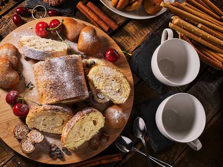 Sand nut chocolate cookies and rolled biscuit on board and cinnamon stick and straw pastry on kitchen on wood table in rustic style top view . Cups of tea and dessert spoon .の写真素材