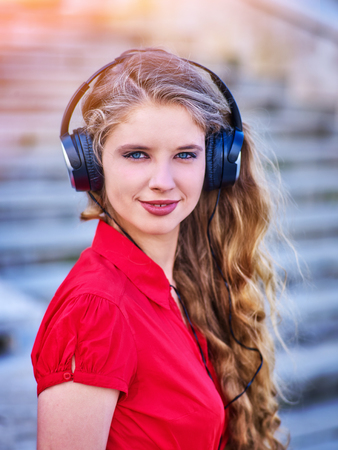 Girl in headphones listens to music and walking down stairs in city. Walking improves blood circulation.の写真素材