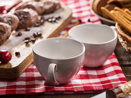 Oatmeal chocolate cookies with coffee grains and cherry, powdered sugar on kitchen cutting board with checkered fabric on wooden table in village style for picnic. Eating junk food.の写真素材
