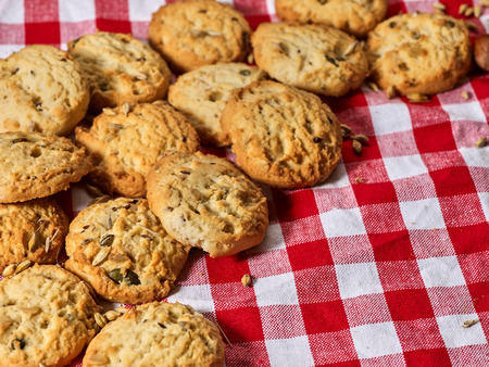 Oatmeal cookies with husk unpeeled oats on kitchen gingham checkered cotton fabric on table in village style copy space with corner.の写真素材