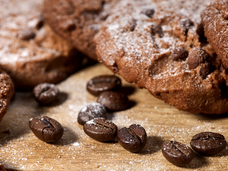 Oatmeal chocolate cookies with coffee grains and cherry, powdered sugar on kitchen cutting board with checkered fabric in village style for picnic. Increase performance and mood.の写真素材
