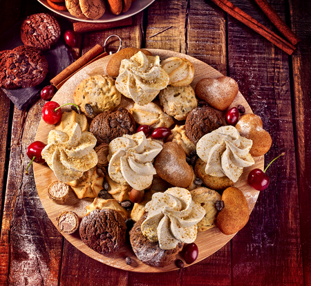 Oatmeal cookies and sand chocolate cake with cherry berry and crispy wafer rolls with cream on cutting board on wooden table in rustic style. Limitations for diabetics. Grandmas recipes.の写真素材