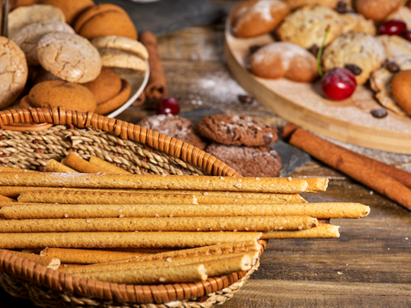 Straw and oatmeal cookies and sand chocolate cake with nut on wooden table in farm style close up.の写真素材