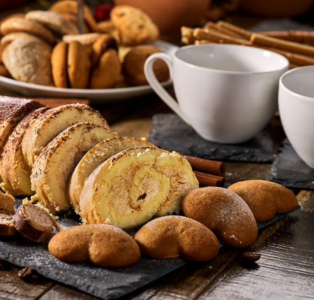 Cookies heart shape, sand rolled biscuit and cinnamon stick on wood table served dessert spoon at kitchen in rustic style. Morning sun flare. Preservation of sugar balance.の写真素材