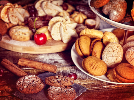 Oatmeal and nut cookies and sand biscuit on tier cake stand, crispy wafer rolls with cream on kitchen on wooden table in rustic natural style. Easily digestible and quickly digestible substances.の写真素材
