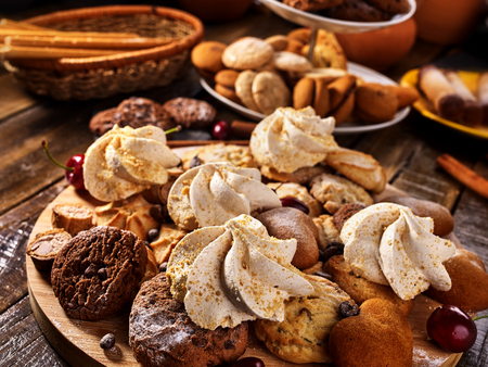 Oatmeal cookies and sand chocolate cake with cherry berry and crispy wafer rolls with cream on cutting board on wooden table in rustic style. Limitations for diabetics. Temptation for gourmet.の写真素材