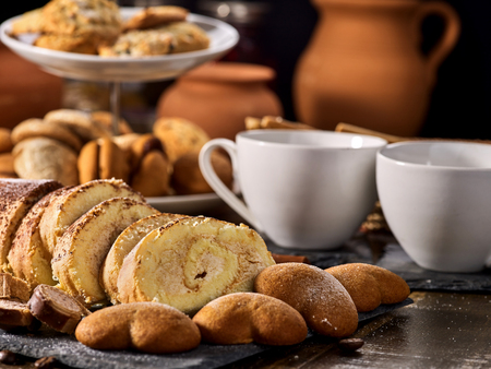 Cookies heart shape, sand rolled biscuit and cinnamon stick on wood table served dessert spoon at kitchen in rustic style. Morning sun flare. Several recipes for baking.の写真素材
