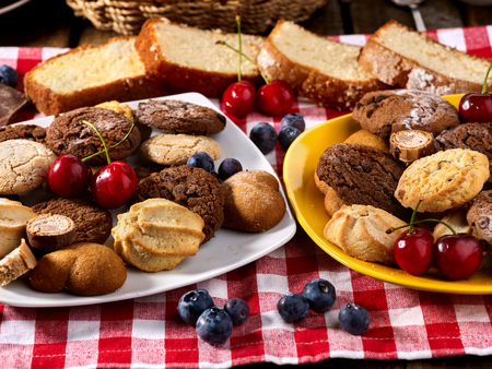 Oatmeal Cookies and sand chocolate cake with blueberries on wooden table in farm style close up. Table setting breakfast for twoの写真素材