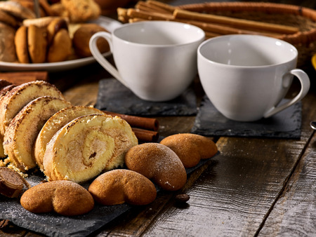 Cookies heart shape, sand rolled biscuit and cinnamon stick on wood table served dessert spoon at kitchen in rustic style. Morning sun flare. Problems with excess weight.の写真素材