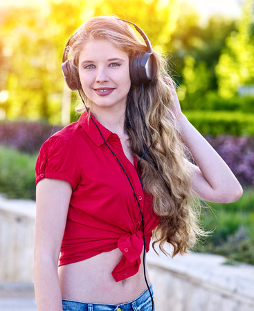 Girl in headphones and denim listens to music with closed eyes and sidewalk walking in city alone. Active participation in social events.の写真素材