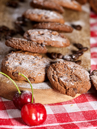 Oatmeal cookies with husk oats and cherry cupcake with powdered sugar on kitchen cutting board gingham checkered cotton fabric on table in village style for picnic. Perfect for breakfast.の写真素材