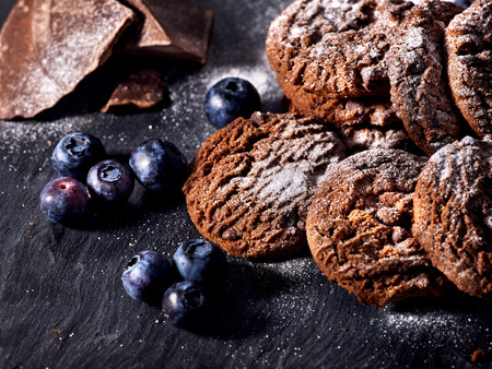 Serving food on slate onto wooden table. Oatmeal cookies biscuit with blueberry on picnic dark tiles countrylike. Chocolate chip cookies tied with string. Dessert in cafe.の写真素材